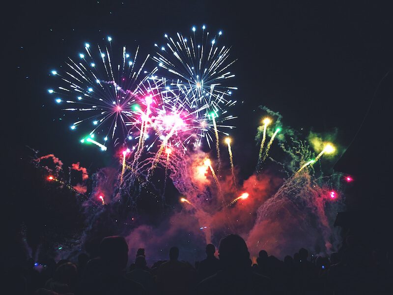 A group of people enjoying fireworks while protecting their hearing. The fireworks are colorful and bright, and they fill the sky with a sense of excitement and joy.