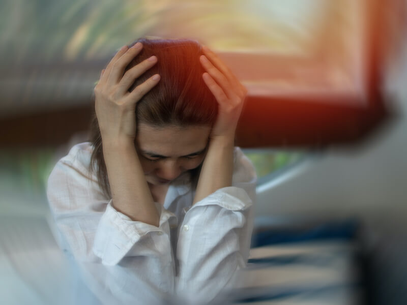 Woman with hands on her head suffering from concussion related tinnitus.