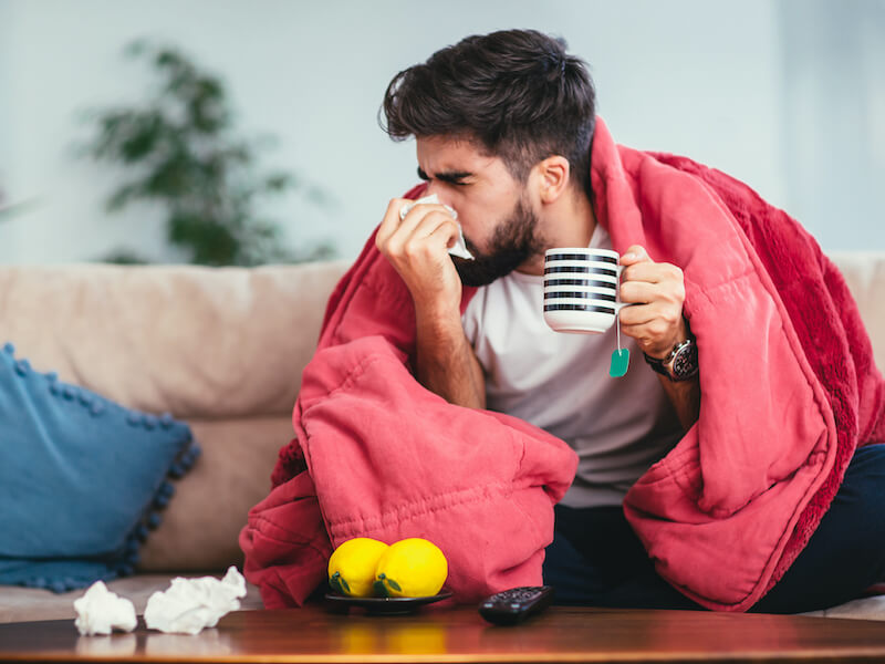 Man blowing his nose sick with a common cold