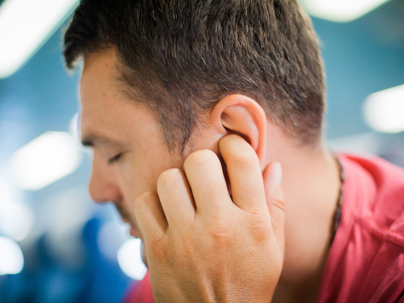 Man holding ear because the constant ringing hurts.