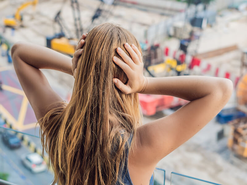 Young girl with hands over her ears to protect against loud noise and hearing loss.