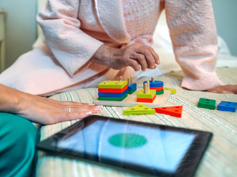 Woman preventing Alzheimers with a puzzle and using hearing aids.