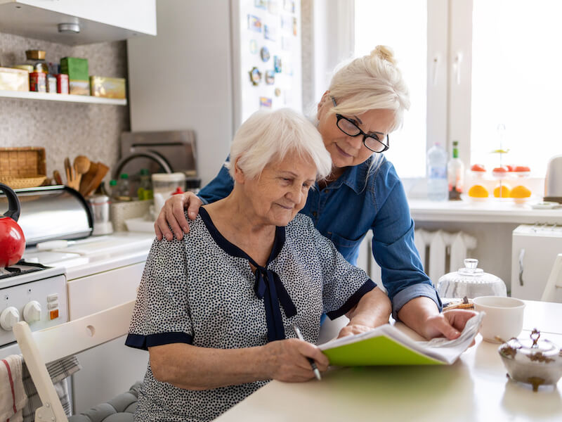 Woman showing her mother information about hearing loss and hearing aids in the kitchen.
