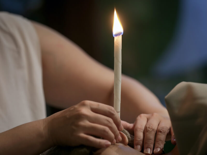 Woman receiving ear candle treatment