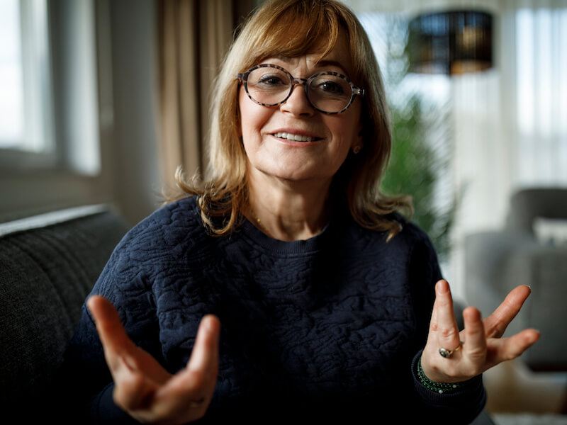 Woman communicating with her hands as she struggles to hear conversation.