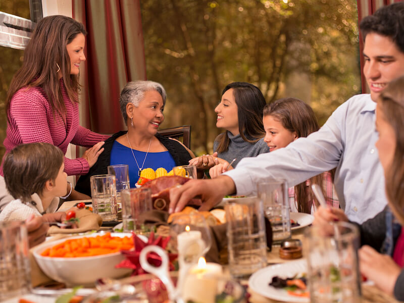 Family enjoying Thanksgiving or Christmas dinner together around the dining table at grandmother's home.